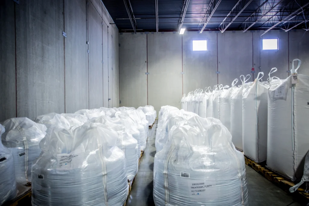 Bulk agriculture materials stored in large white tote bags on pallets inside a 3PL warehouse in Indiana